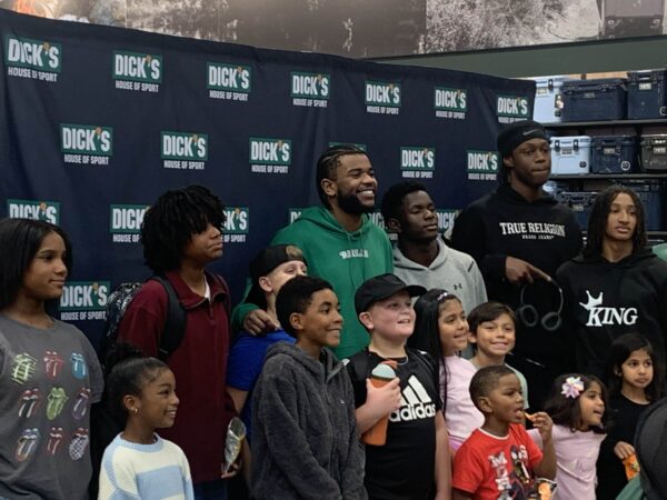Jaden Hardy smiling while helping kids shop during a holiday event