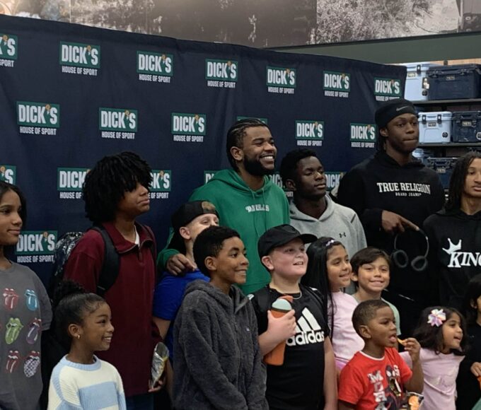 Jaden Hardy smiling while helping kids shop during a holiday event