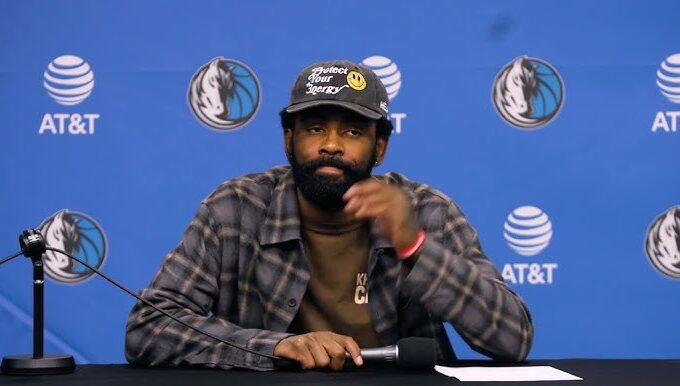 Kyrie Irving watches Dallas Mavericks teammates test drive custom golf carts during a holiday team gift moment.