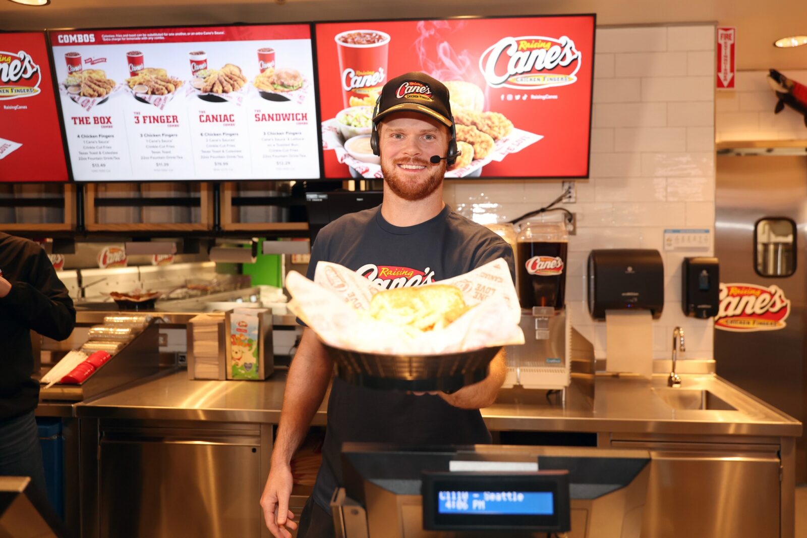Sam Darnold wearing a headset and serving customers at a University District restaurant after his championship win.