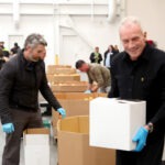 Joe Montana volunteering with Guinness team at SF-Marin Food Bank repacking meals
